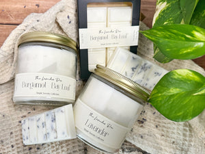 Candles and wax melt bars on a wooden surface with fabric and plant accents