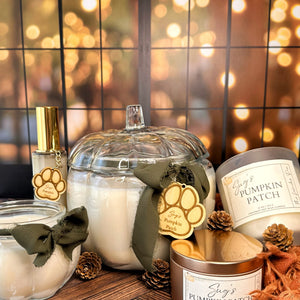 Group of candles in various containers. Features a room spray bottle all on a wooden surface with fairy lights in the background. 