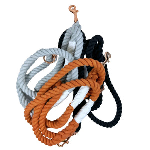 Three rope leashes grouped together. One is burnt orange, one is light gray, and one is black. All have a rose gold keychain clasp.