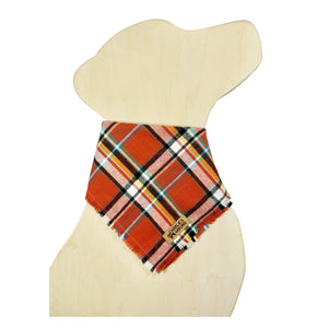Plaid bandana on a dog-shaped wooden cutout. Plaid features colors of rust, blue, yellow-orange, and black.