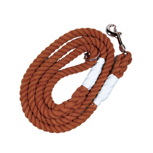 Burnt orange colored rope dog leash with rose gold hardware and charm coiled up a white background. 