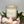 Candle labeled 'Dewey's Spring' surrounded by flowers on a wooden surface.
