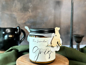 Candle jar labeled 'Grief' on a wooden stand with a green cloth background