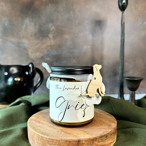Candle jar labeled 'Grief' on a wooden stand with a green cloth background