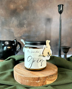 Candle jar labeled 'Grief' on a wooden stand with a green cloth background