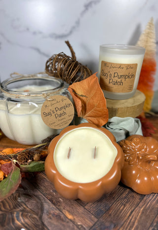 Photo showing all available sizes of our Sug's Pumpkin Patch candle. Surrounding the candles are fall leaves and wood accents.