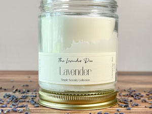 Lavender candle with a label on a wooden surface with lavender petals.