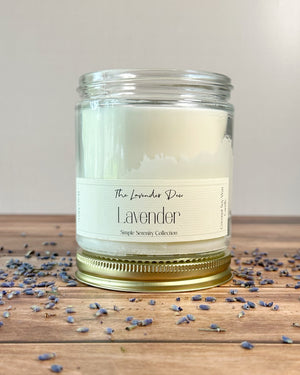 Lavender candle with a label on a wooden surface with lavender petals.
