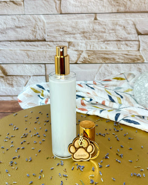 Clear bottle with gold lid and paw print charm on a gold tray with fabric details and a break background