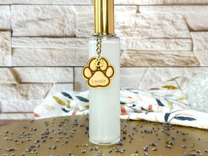 Clear bottle room spray with gold lid and paw print charm on a gold tray and brick background