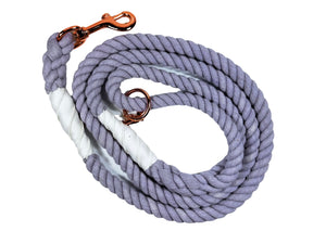 Lavender colored rope dog leash with rose gold hardware and charm coiled up a white background. 
