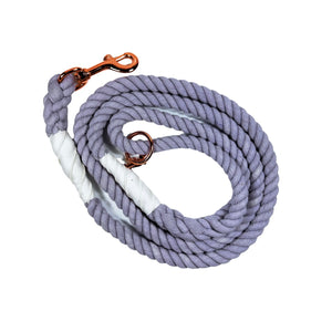 Lavender colored rope dog leash with rose gold hardware and charm coiled up a white background. 