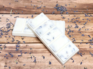 Three white wax melt bars with lavender petals on a wooden surface