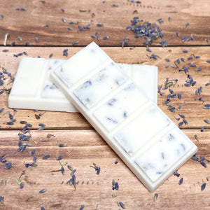 Three white wax melt bars with lavender petals on a wooden surface