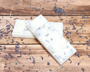 Three white wax melt bars with lavender petals on a wooden surface