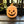 Terracotta jack-o'-lantern on a wooden surface with green leaves in the background