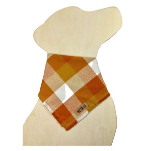 Plaid flannel bandana on a dog-shaped wooden cutout. The plaid fabric has shades of orange, red-orange, and white.