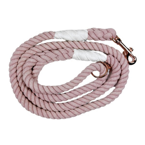 Rose colored rope dog leash with rose gold hardware and charm coiled up a white background. 
