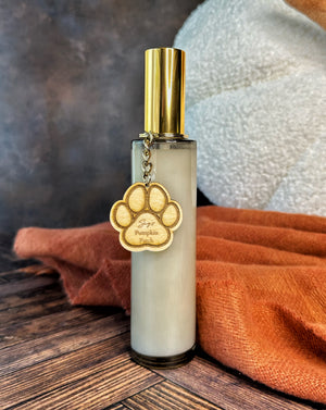 Room spray bottle with gold cap and paw print design on a wooden surface