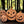 Four terracotta jack-o'-lantern on a wooden surface with green leaves in the background