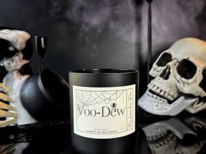 Black candle labeled 'Voo-Dew' with Halloween-themed decorations in the background