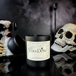 Black candle labeled 'Voo-Dew' with Halloween-themed decorations in the background