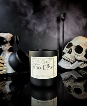 Black candle labeled 'Voo-Dew' with Halloween-themed decorations in the background