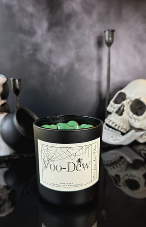 Black candle labeled 'Voo-Dew' with Halloween-themed decor in the background