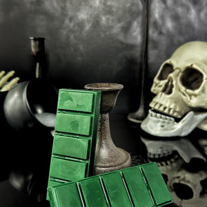 Green colored wax melt snap bars on a black background with skull and cauldron accents