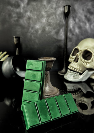 Green colored wax melt snap bars on a black background with skull and cauldron accents